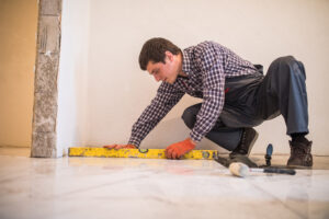 Home tile improvement - handyman with level laying down tile floor